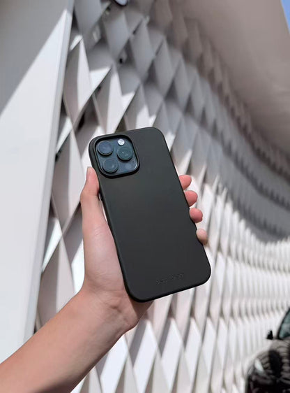 Hand holding a black silicone iPhone 16 pro case against a geometric wall background