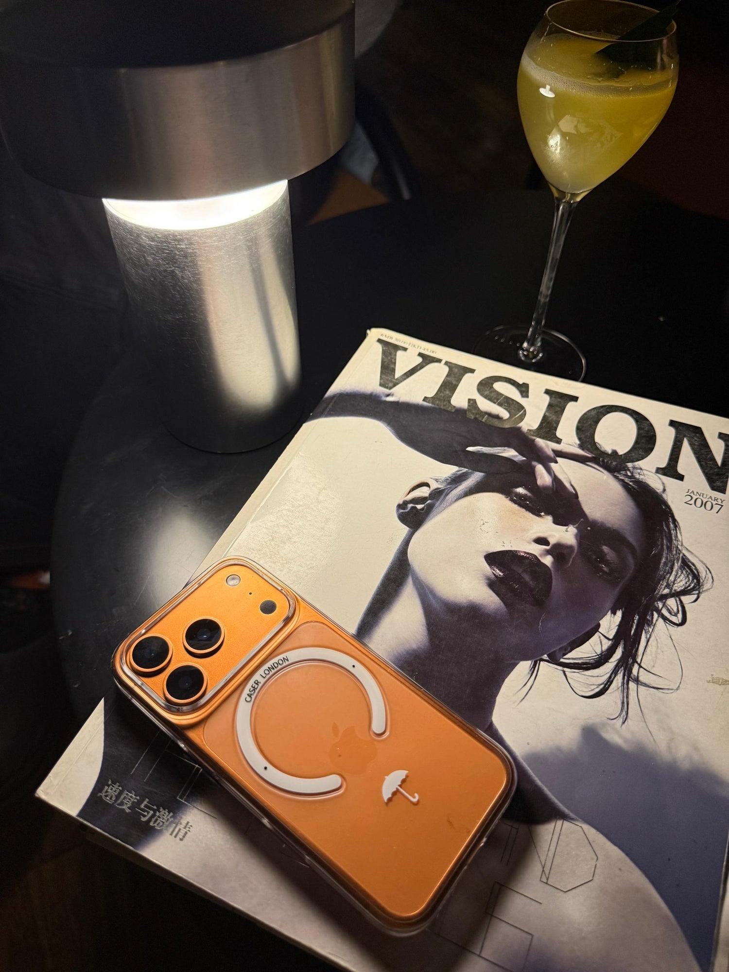 CASER LONDON the iconic case with umbrella icon on a magazine next to a cocktail